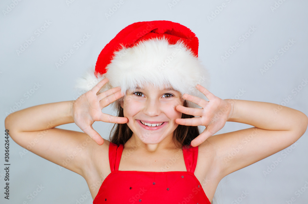 Wall mural Little cute girl smiles in a santa hat