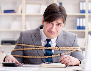 Businessman tied up with rope in office
