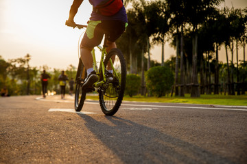 Man ride on bike on the road. Sport and active life concept sunset time. Couple of men riding on bicycle in a park. Blue sky with orange sun beam over the body of cyclist.