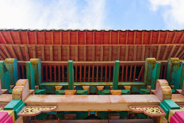 bright red old wooden canopy in good condition after restoration rests on multi-colored columns and...