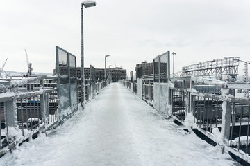 icy pedestrian bridge over a railway station in an industrial area of a big city on a frosty winter day