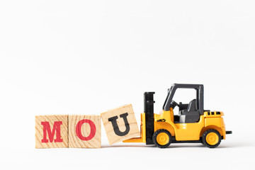 Toy forklift hold wood letter block U to complete word MOU (Abbreviation of memorandum of understanding) on white background