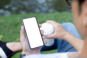 Mockup image blank white screen cell phone.men hand holding texting using mobile sitting in park.background empty space for advertise text.people contact marketing business and technology 