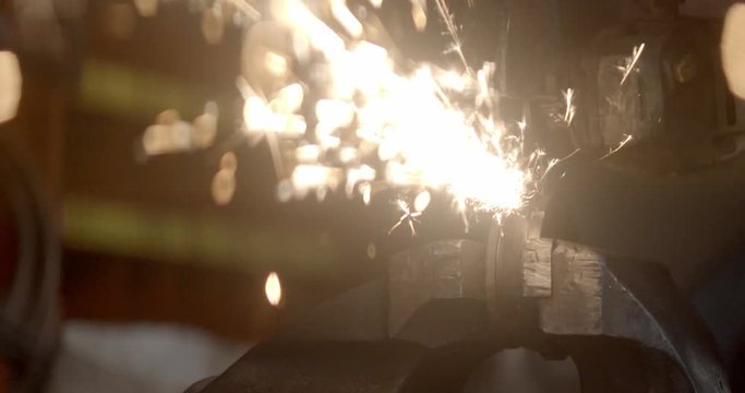 Steel worker with angle grinder making hot glowing sparks