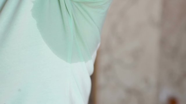 Hyperthyroidism concept. Nasty smell from sweat. Close-up of wet underarm. Young woman with sweat stain on her clothes against grey background.