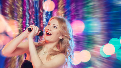 Beautiful young woman singing with microphone in night club