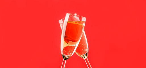Two champagne flutes make cheers on red light bokeh background banner
