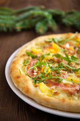Pizza with turkey, bacon, orange and cashew nuts on dark wooden background