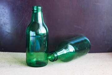 Two green bottles on a brown background. Two small bottles with a narrow neck of green glass on a...