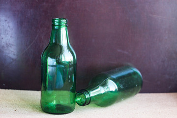Two green bottles on a brown background. Two small bottles with a narrow neck of green glass on a...