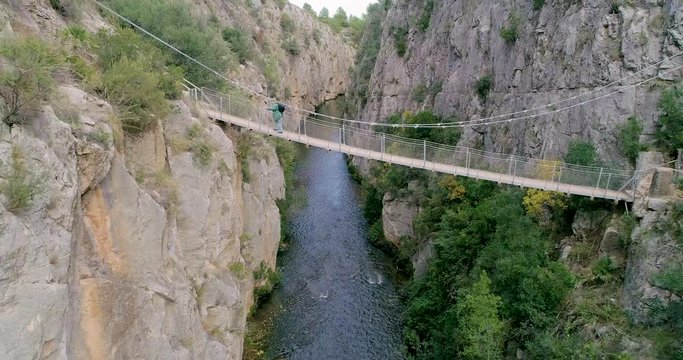 Anciano cruzando puente colgante sobre ca&ntilde;&oacute;n de rio de paredes verticales y profundas