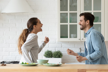 Happy active young couple having fun dancing together in kitchen
