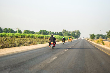 villager are taking their families on the bikes without helmets on a fast speed highway   