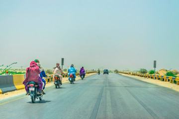Obraz premium villager are taking their families on the bikes without helmets on a fast speed highway 