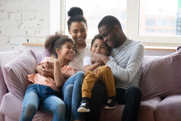 Happy biracial family with kids relax on cozy sofa