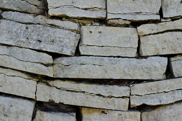 Close up texture view of an old sagging stone block wall with gray color stone bricks