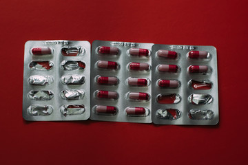 Medicines on red background. Treatment of diseases.