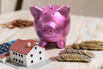 Dreaming a new home concept. Calculating savings, model house and piggy bank