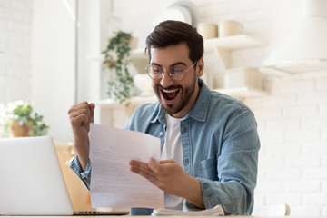 Fototapeta na wymiar Excited man reading postal mail letter overjoyed by good news