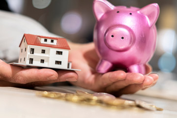 Saving money and dreaming a new home concept. Coins, model house and piggy bank