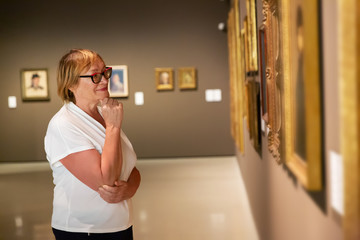 Fototapeta na wymiar Woman examining exposition in fine arts museum