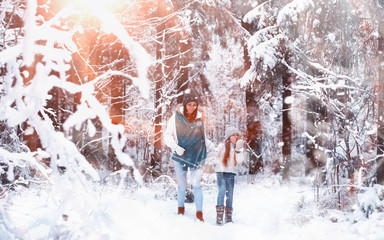 Young family for a walk. Mom and daughter are walking in a winter park.