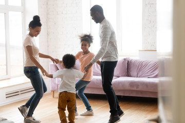 Happy african American family with kids dance together at home