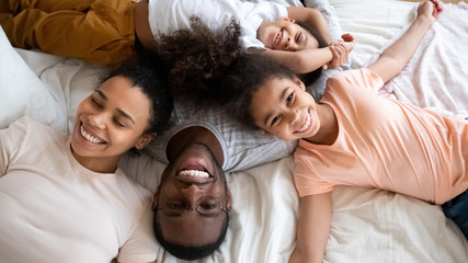 Top view of happy biracial family relaxing on bed