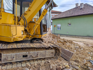 Excavator machine clearing up space for building and renovating new house in neighborhood. Heavy machinery industrial excavation.