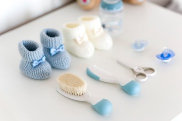Fototapeta na wymiar knitted baby shoes with milk bottle, scissors, pacifier and baby comb