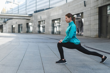 Fototapeta na wymiar Young adult girl stretching legs before running training
