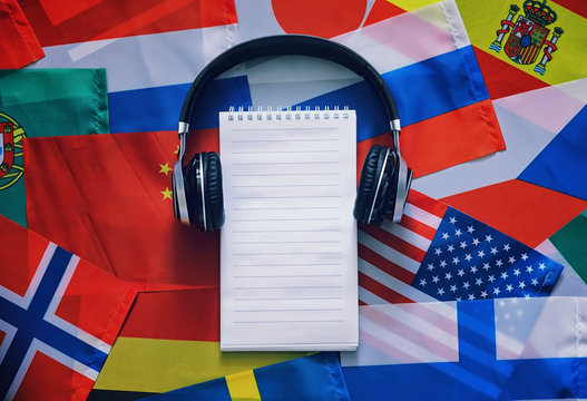 Learning foreign languages. Audio language courses. Background from countries flags and headphones on the table.