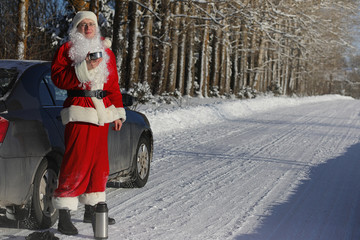 Santa Claus comes with gifts from the outside. Santa in a red suit with a beard and wearing glasses is walking along the road to Christmas. Father Christmas brings gifts to children.