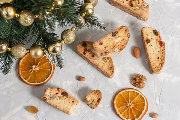 Traditional Italian biscotti or Cantuccini cookies with hazelnuts, almonds, walnuts on a gray background with slices of dried oranges and a Christmas tree. The concept of Christmas baking