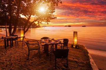 Romantic sunset on the shore of a tropical island. Cafe on the beach.