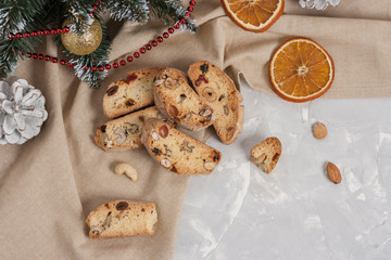 Traditional Italian cookie Biscotti or Cantuccini with hazelnuts, almonds, walnuts on a gray background with a beige linen napkin and slices of dried oranges .Christmas and New Year baking.