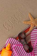 Fototapeta na wymiar Word MIAMI written in sand with beach accessories.