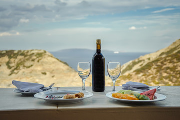 Wine and food against the backdrop of the sea and mountains. - obrazy, fototapety, plakaty