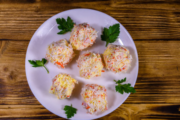 White plate with crab-cheese balls on wooden table. Top view