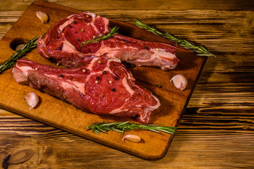 Raw ribeye steak, spices, rosemary and garlic on cutting board
