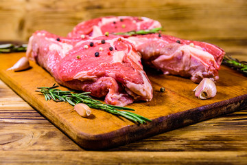 Raw ribeye steak, spices, rosemary and garlic on cutting board