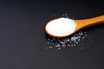 Scoop of white sugar on black background with copy spacce