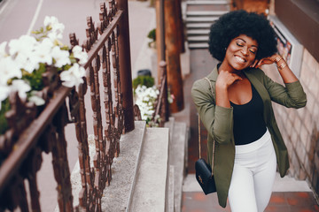 Fashionable girl in a summer city. Black lady in a green jacket