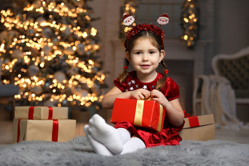 Fototapeta na wymiar Cute little child with Christmas gift in living room