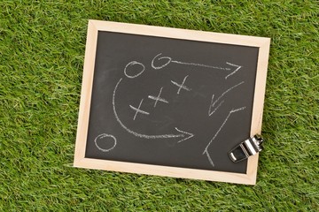 Soccer sports referee chrome whistle with game strategy drawing blackboard on grass background -...