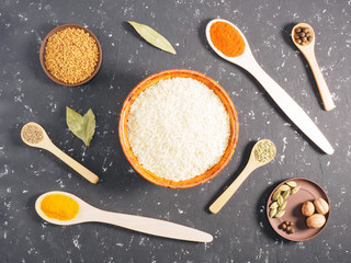 Rice and spices on a black concrete background. Indian cuisine ingredients