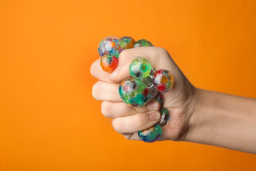 Woman squeezing colorful slime on orange background, closeup. Antistress toy