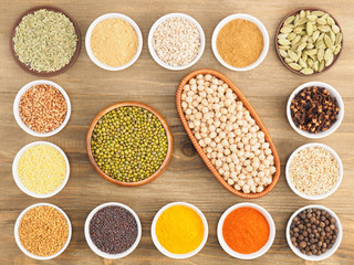 Buckwheat, oat, mung bean, chick pea, millet, green cardamom, allspice, dry ginger, pepper chili, fenugreek, turmeric, cloves, masala, mustard seeds on brown wooden background. 