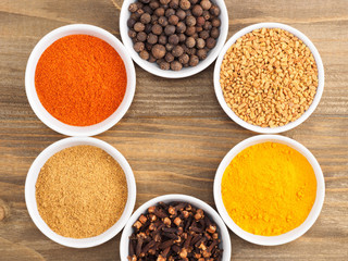 Allspice, pepper chili, fenugreek, cloves, turmeric, masala on brown wooden background. Indian cuisine, ayurveda, naturopathy concept