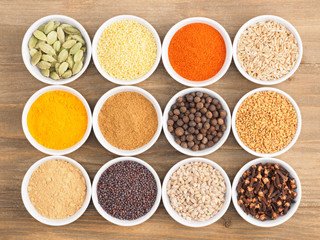 Allspice, pepper chili, fenugreek, cloves, turmeric, millet, oat, buckwheat, green cardamom, dry ginger, masala on brown wood background. Indian cuisine, ayurveda, naturopathy concept